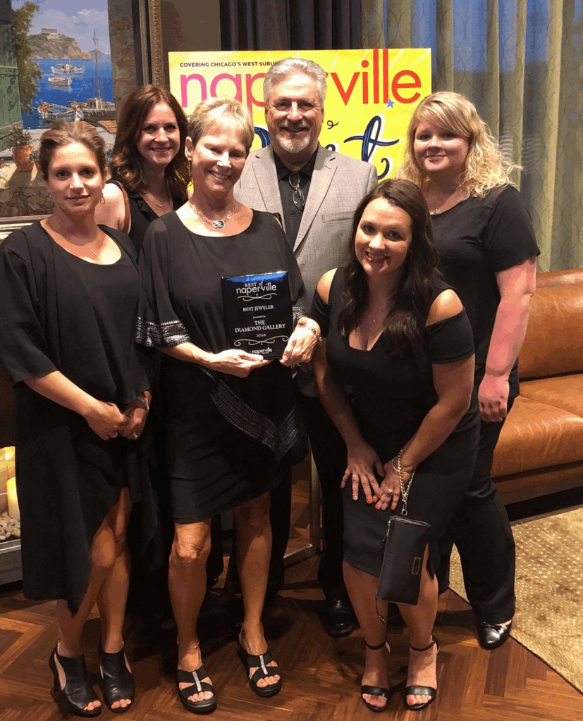 Group photo of six people, five women and one man, at an event with an award.